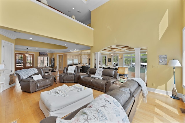 living room with ornamental molding, a wealth of natural light, a chandelier, and light wood-type flooring