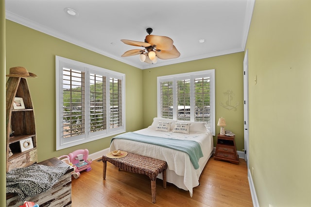 bedroom featuring crown molding, light hardwood / wood-style floors, and multiple windows