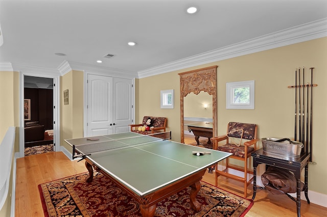 recreation room with ornamental molding and light hardwood / wood-style floors