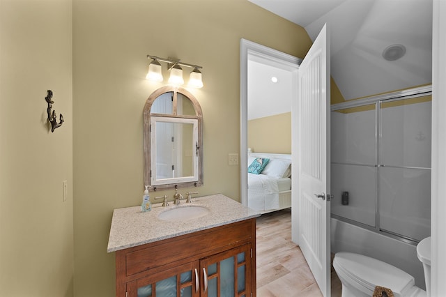 full bathroom with toilet, wood-type flooring, bath / shower combo with glass door, vaulted ceiling, and vanity