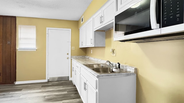 3709 Firethorne Dr, Memphis, TN 38115 - kitchen with wood-type flooring, sink, white cabinets, and a textured ceiling