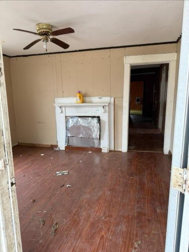 unfurnished living room with a fireplace, dark hardwood / wood-style floors, and ceiling fan