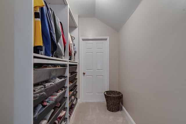 walk in closet with lofted ceiling and light carpet