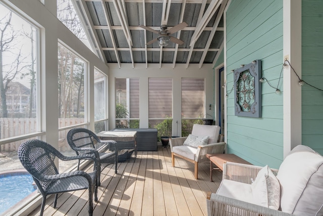 sunroom featuring ceiling fan, a healthy amount of sunlight, and vaulted ceiling with beams