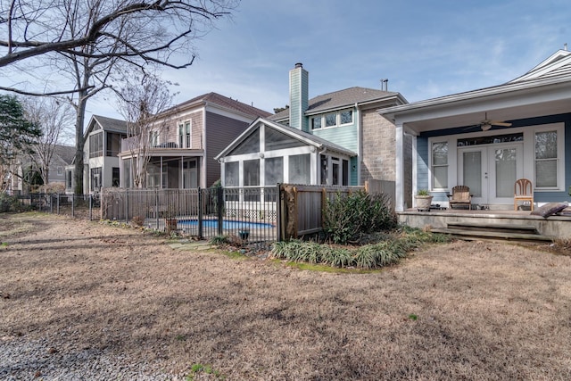 rear view of house with ceiling fan, a swimming pool side deck, a sunroom, and a lawn