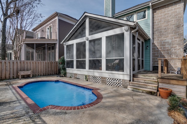 rear view of property featuring a fenced in pool, a balcony, a sunroom, and a patio area