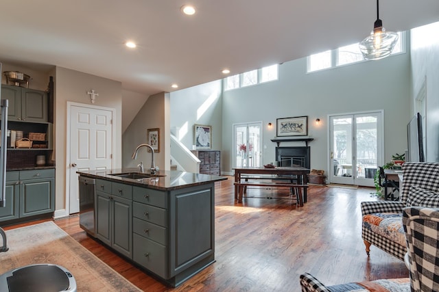 kitchen featuring pendant lighting, dishwasher, an island with sink, sink, and gray cabinetry