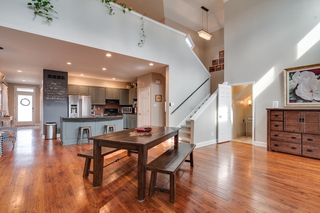 dining space with sink, light hardwood / wood-style floors, and a high ceiling