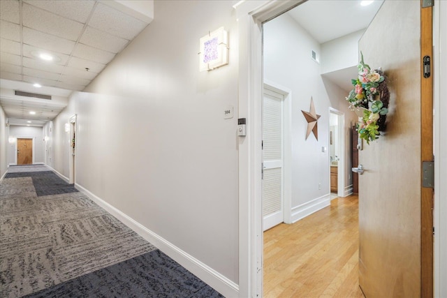 hall featuring a drop ceiling and light hardwood / wood-style floors