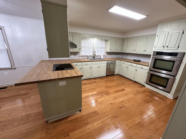 kitchen featuring appliances with stainless steel finishes, kitchen peninsula, sink, and light wood-type flooring