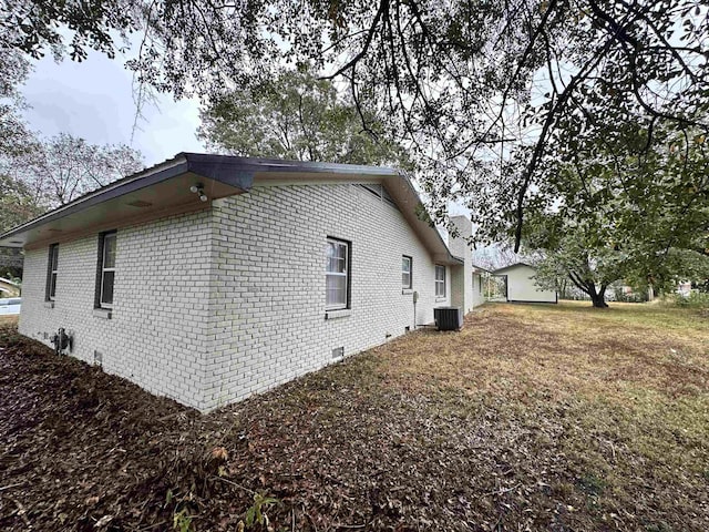 view of side of home with a yard and central air condition unit