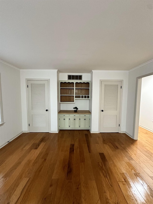 unfurnished living room with ornamental molding and hardwood / wood-style floors