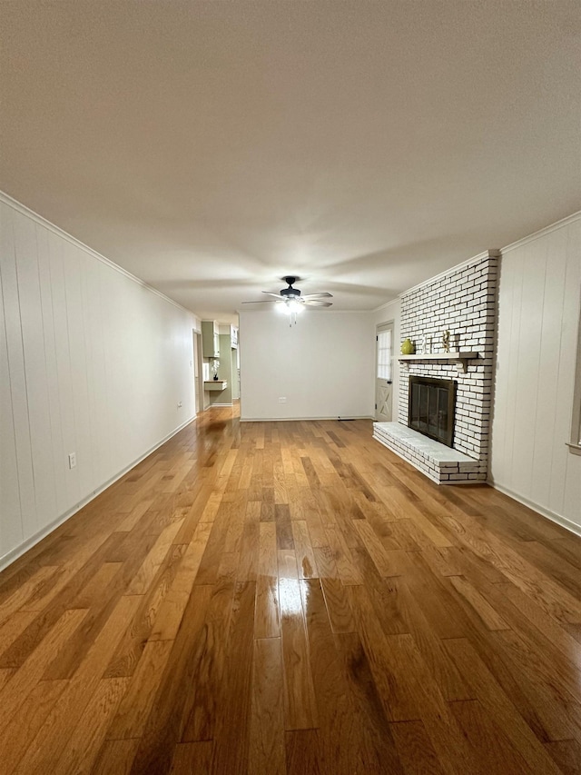 unfurnished living room with hardwood / wood-style floors, a fireplace, ornamental molding, and ceiling fan