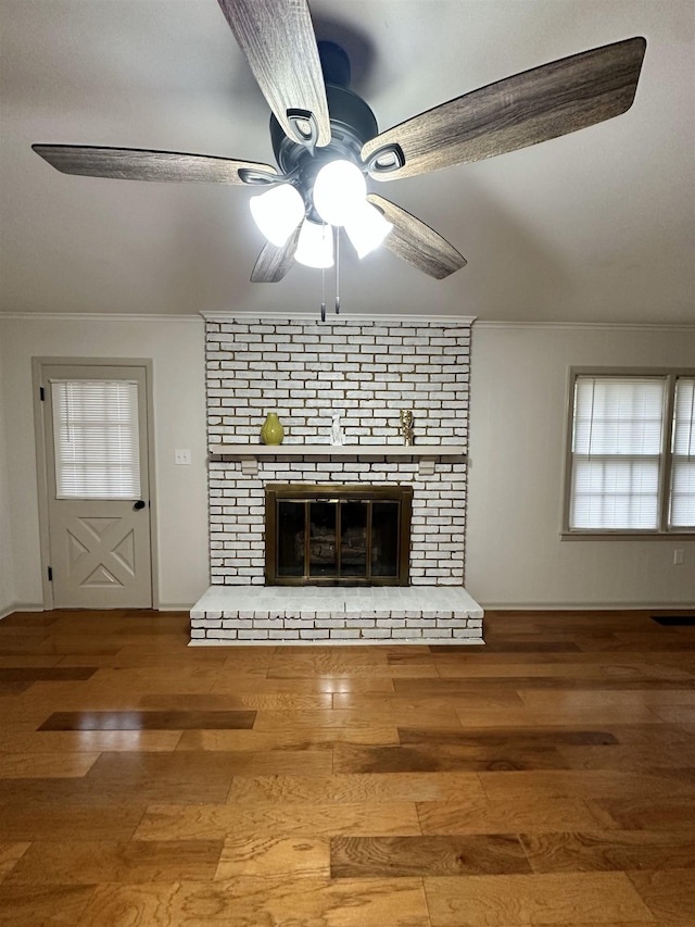 unfurnished living room featuring crown molding, a brick fireplace, hardwood / wood-style floors, and ceiling fan