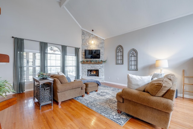 living room with crown molding, a stone fireplace, light hardwood / wood-style flooring, and high vaulted ceiling