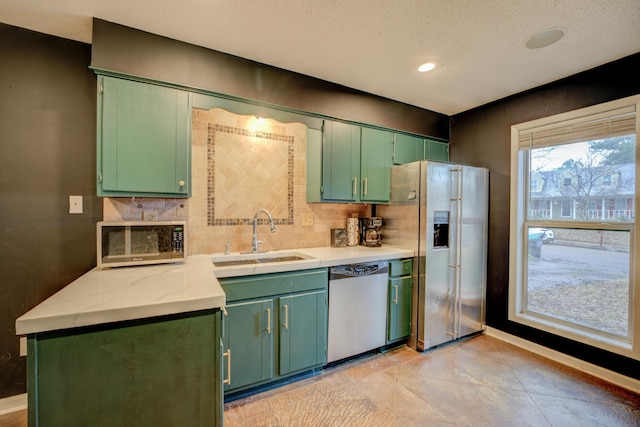 kitchen with tasteful backsplash, appliances with stainless steel finishes, sink, and green cabinets