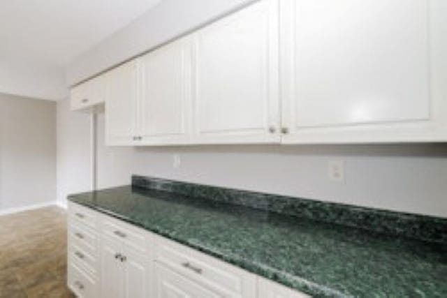 kitchen with white cabinetry and carpet