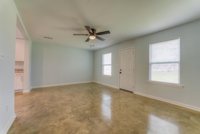 empty room with ceiling fan and concrete floors