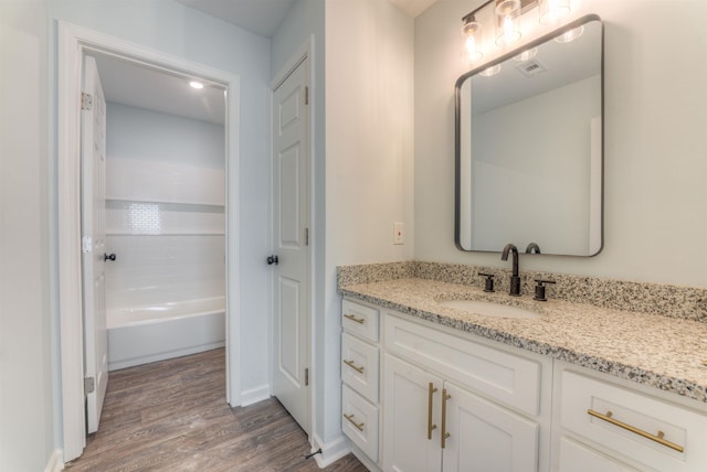 bathroom featuring vanity, wood-type flooring, and bathtub / shower combination