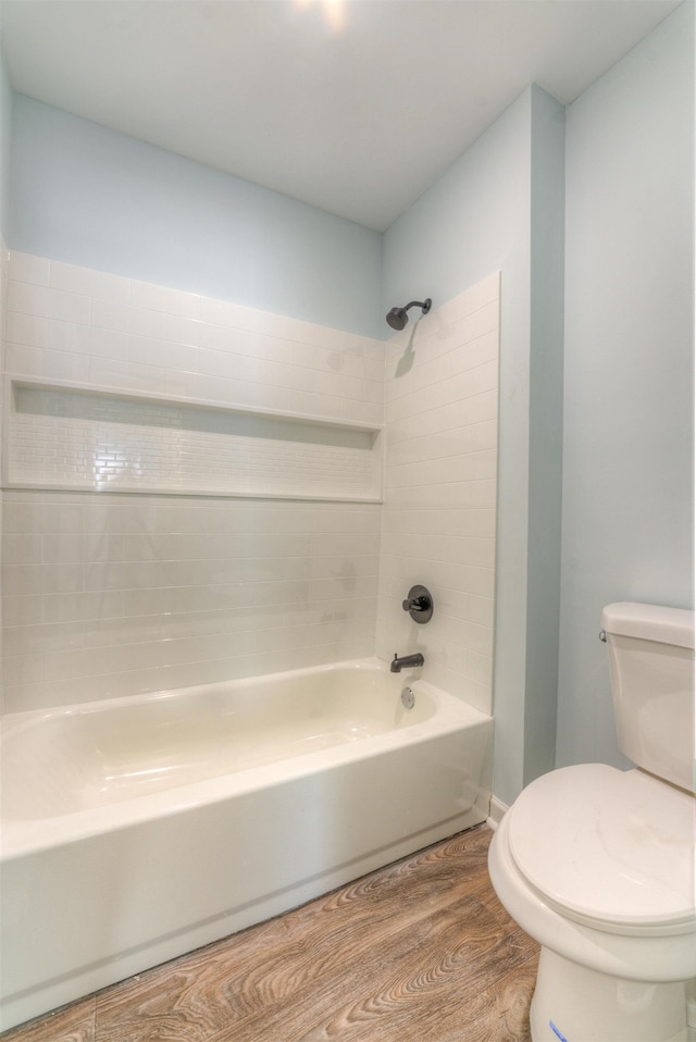 bathroom with hardwood / wood-style flooring, tiled shower / bath, and toilet