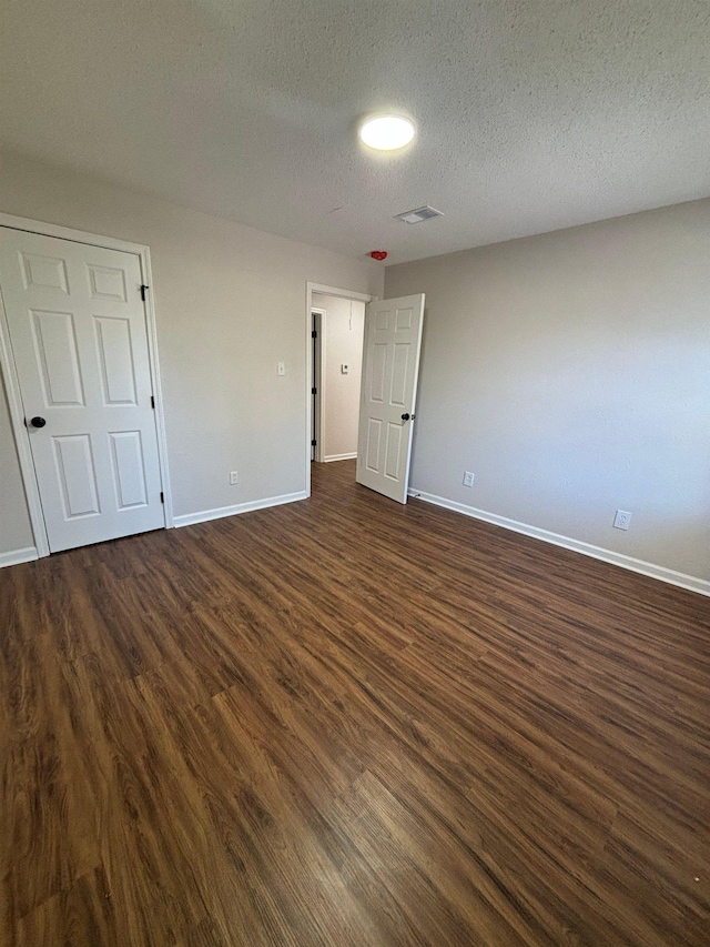 unfurnished bedroom featuring dark wood-type flooring and a textured ceiling