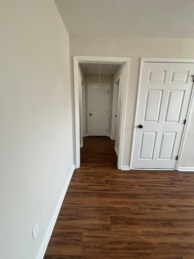 hall with dark hardwood / wood-style floors and a textured ceiling