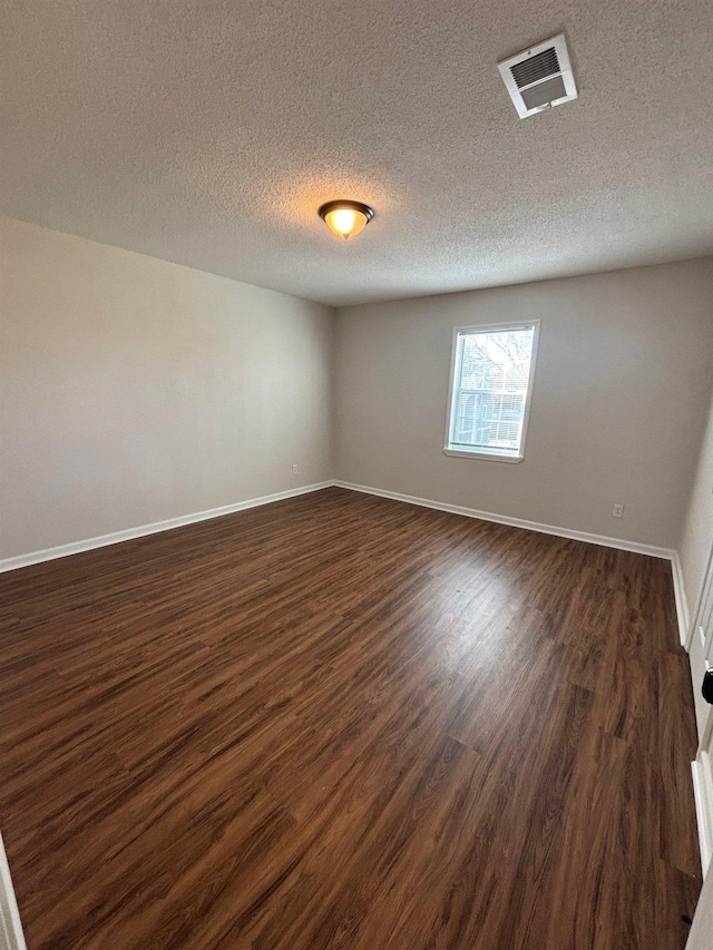 unfurnished room featuring dark wood-type flooring and a textured ceiling