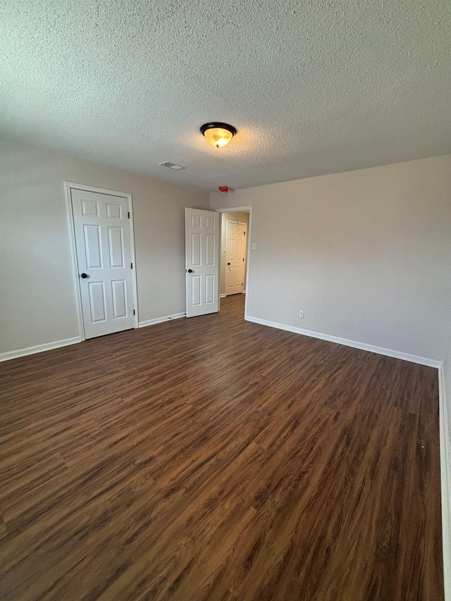 unfurnished bedroom featuring a textured ceiling and dark hardwood / wood-style flooring