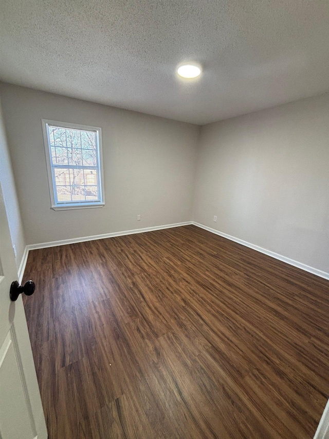 unfurnished room with dark hardwood / wood-style flooring and a textured ceiling