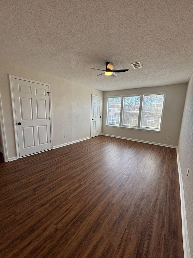 interior space featuring dark wood-type flooring, a textured ceiling, and ceiling fan