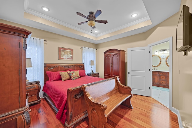 bedroom featuring a raised ceiling, ornamental molding, and light hardwood / wood-style flooring