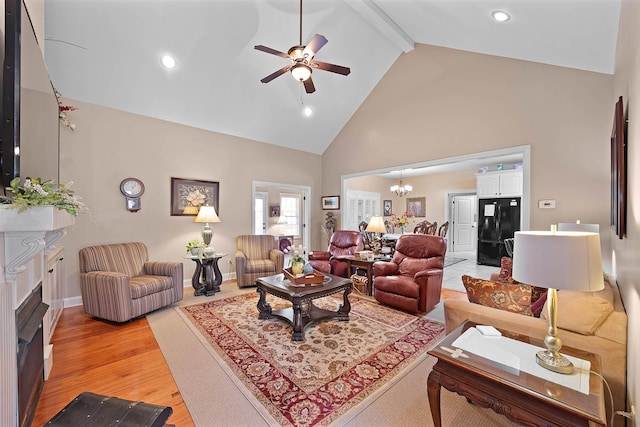 living room with beam ceiling, light wood-type flooring, ceiling fan with notable chandelier, and high vaulted ceiling