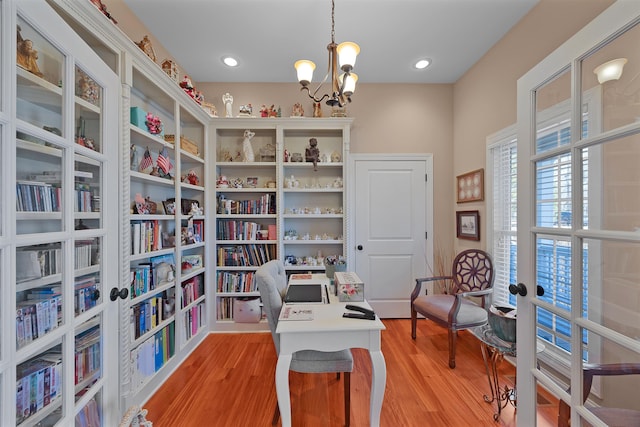 home office with a chandelier, light hardwood / wood-style floors, and french doors