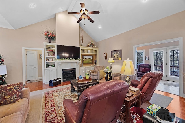 living room with beam ceiling, light hardwood / wood-style flooring, high vaulted ceiling, and ceiling fan