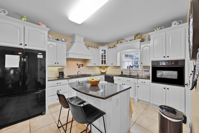 kitchen with sink, a kitchen breakfast bar, black appliances, custom range hood, and white cabinets