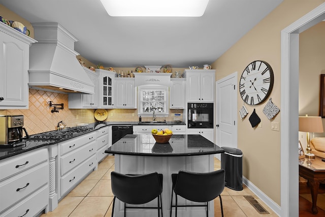 kitchen featuring a kitchen island, white cabinetry, sink, custom exhaust hood, and black appliances