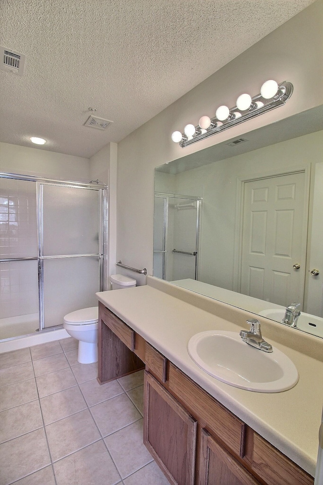 bathroom with tile patterned flooring, an enclosed shower, vanity, a textured ceiling, and toilet