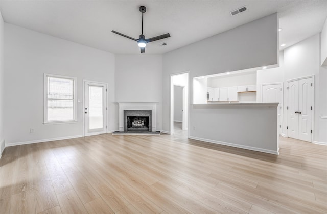 unfurnished living room featuring high vaulted ceiling, light hardwood / wood-style floors, and ceiling fan