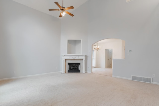 unfurnished living room featuring high vaulted ceiling, ceiling fan with notable chandelier, and light colored carpet