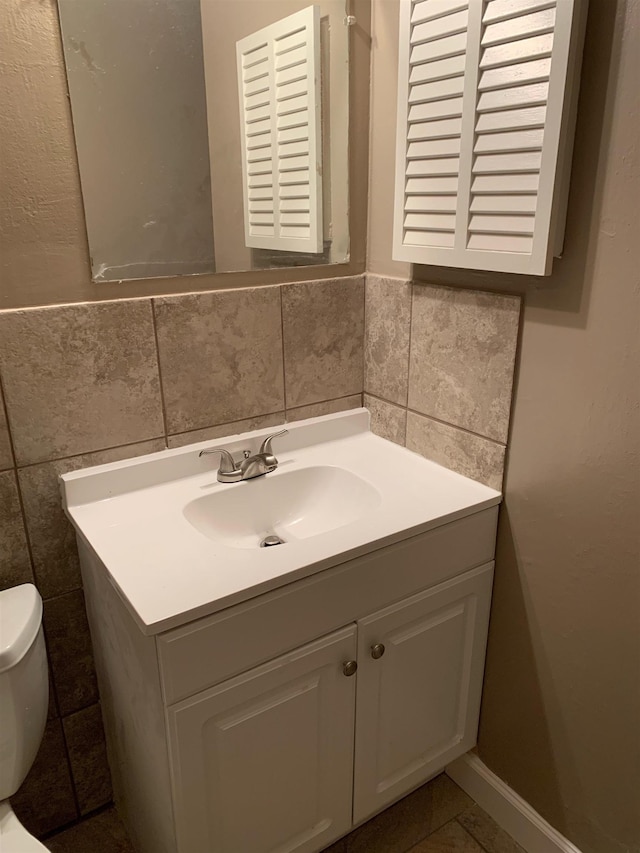 bathroom featuring vanity, tile walls, and toilet