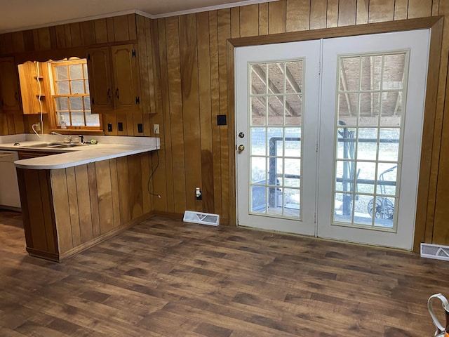 kitchen featuring sink, dishwasher, dark hardwood / wood-style floors, kitchen peninsula, and wood walls