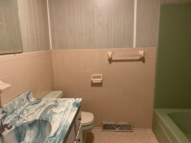 bathroom featuring tile patterned flooring, vanity, tile walls, and toilet