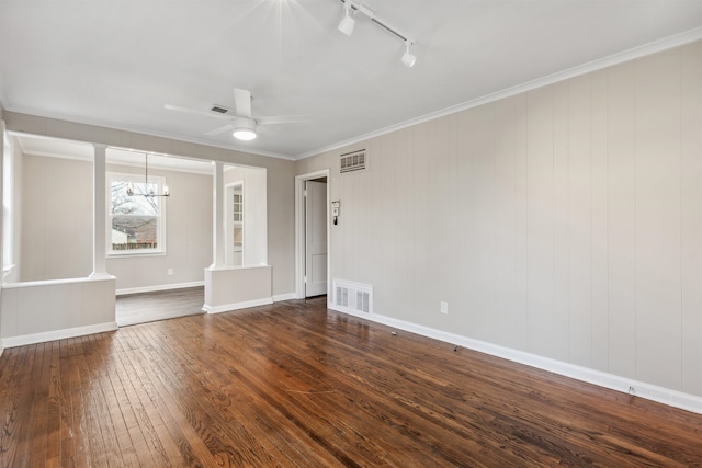 empty room featuring dark hardwood / wood-style floors, ceiling fan with notable chandelier, decorative columns, rail lighting, and crown molding