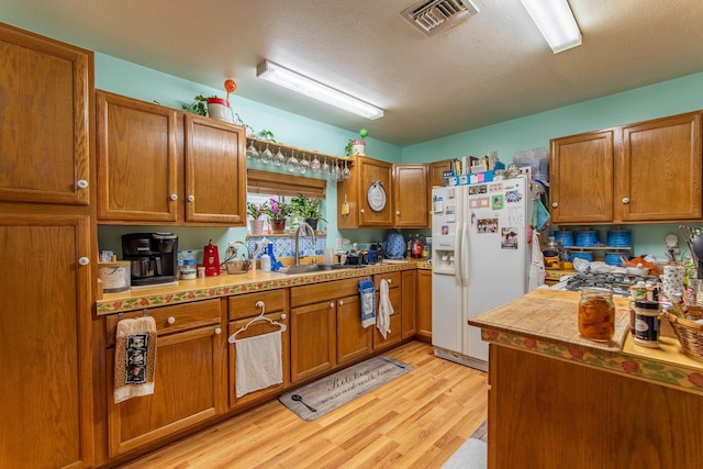 kitchen featuring white refrigerator with ice dispenser, sink, and light hardwood / wood-style floors