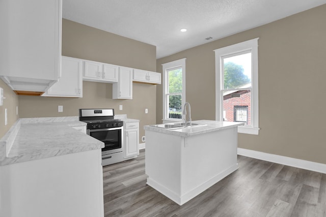 kitchen with sink, white cabinetry, a center island, light hardwood / wood-style floors, and stainless steel range with gas cooktop