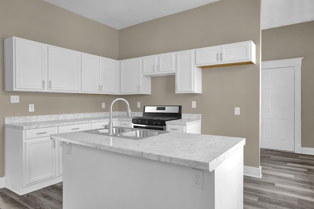 kitchen with gas range, white cabinetry, sink, and a center island with sink