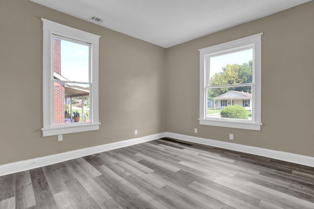 unfurnished room with a textured ceiling and light wood-type flooring