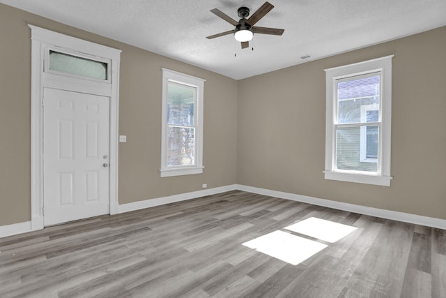 foyer entrance with ceiling fan, a textured ceiling, and light hardwood / wood-style flooring