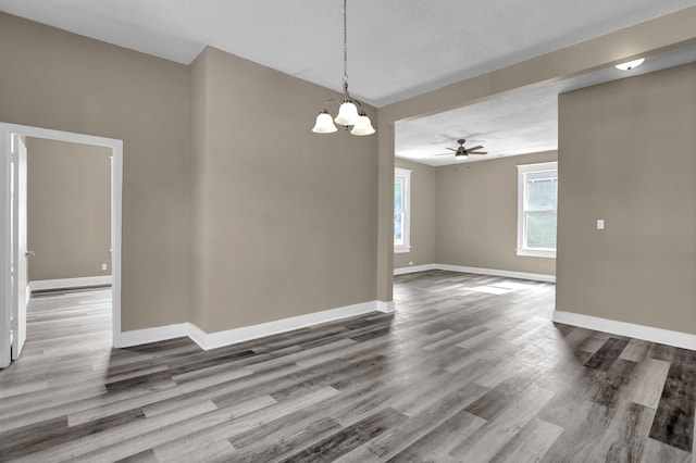 spare room featuring hardwood / wood-style flooring, ceiling fan with notable chandelier, and a textured ceiling