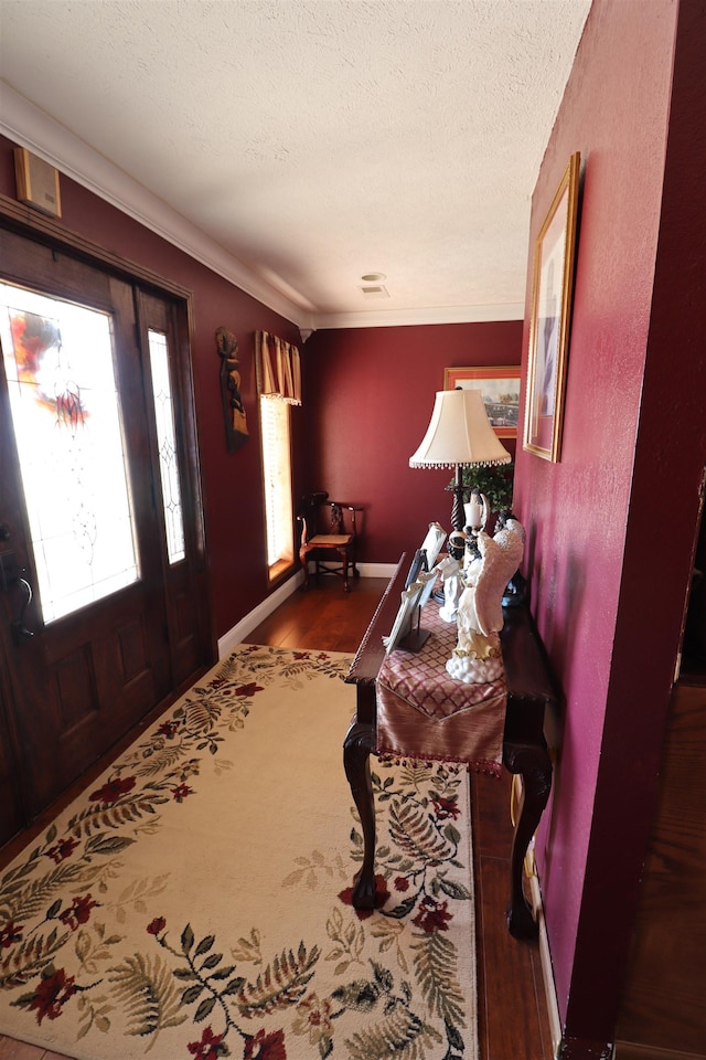 foyer with crown molding, wood-type flooring, and a textured ceiling